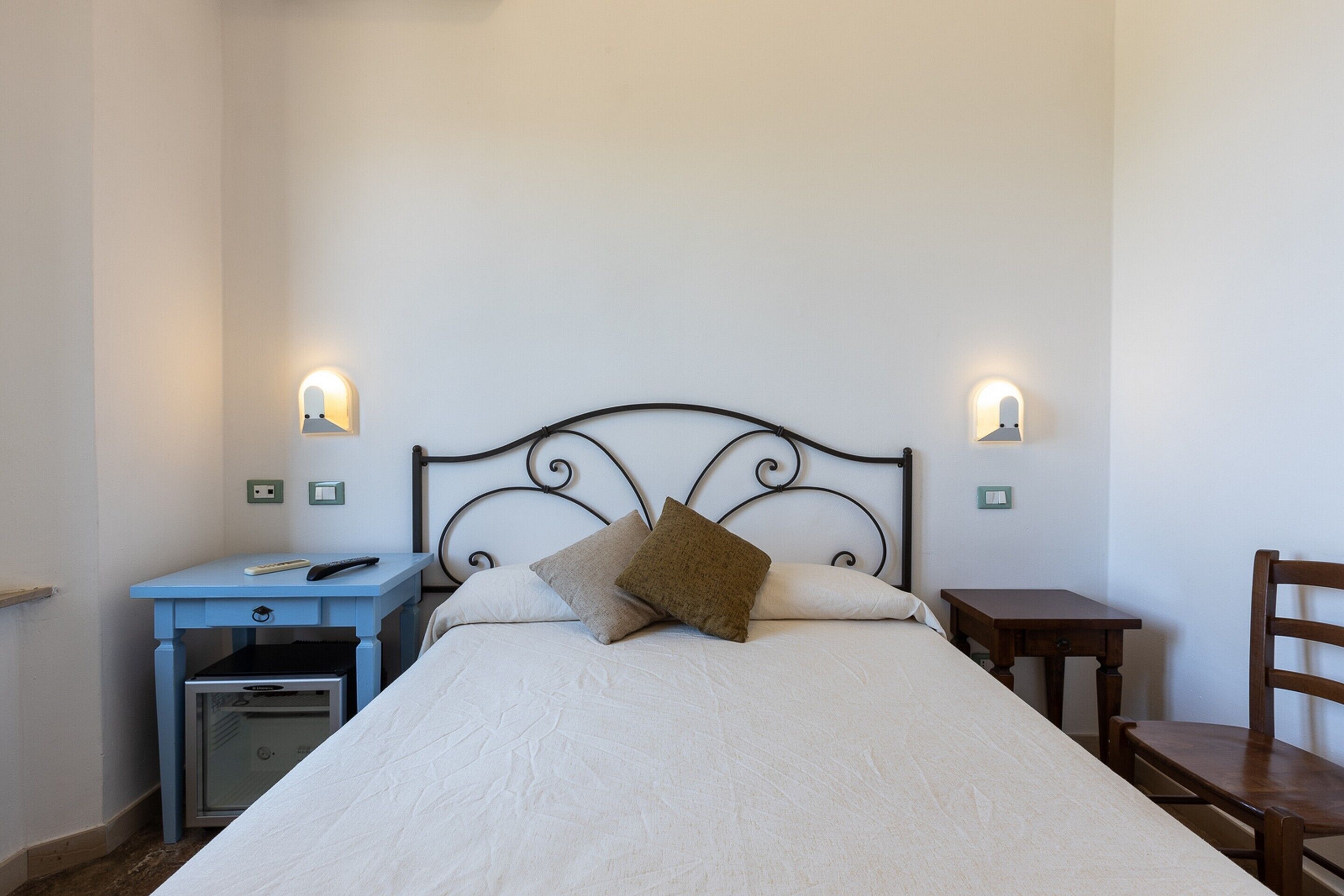 Un dormitorio con cama, mesitas de noche, escritorio y una silla.