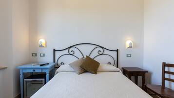 Un dormitorio con cama, mesitas de noche, escritorio y una silla.