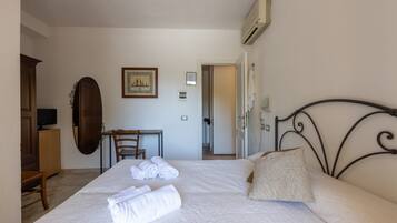 Una habitación de hotel con cama, escritorio, silla, televisor y aire acondicionado.