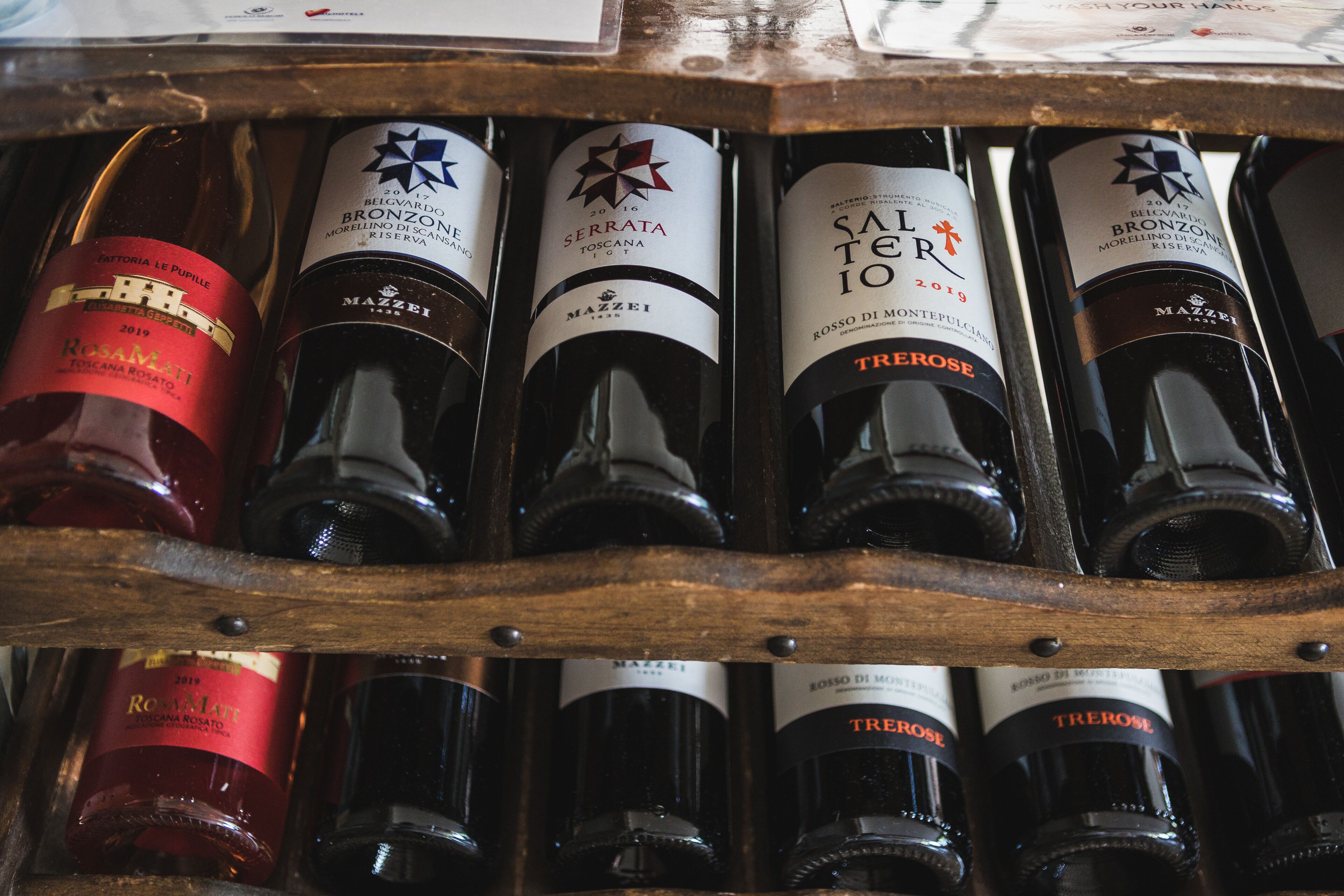 Un présentoir en bois contenant plusieurs bouteilles de vin, dont des marques comme « Rosamonte » et « Tierra ».