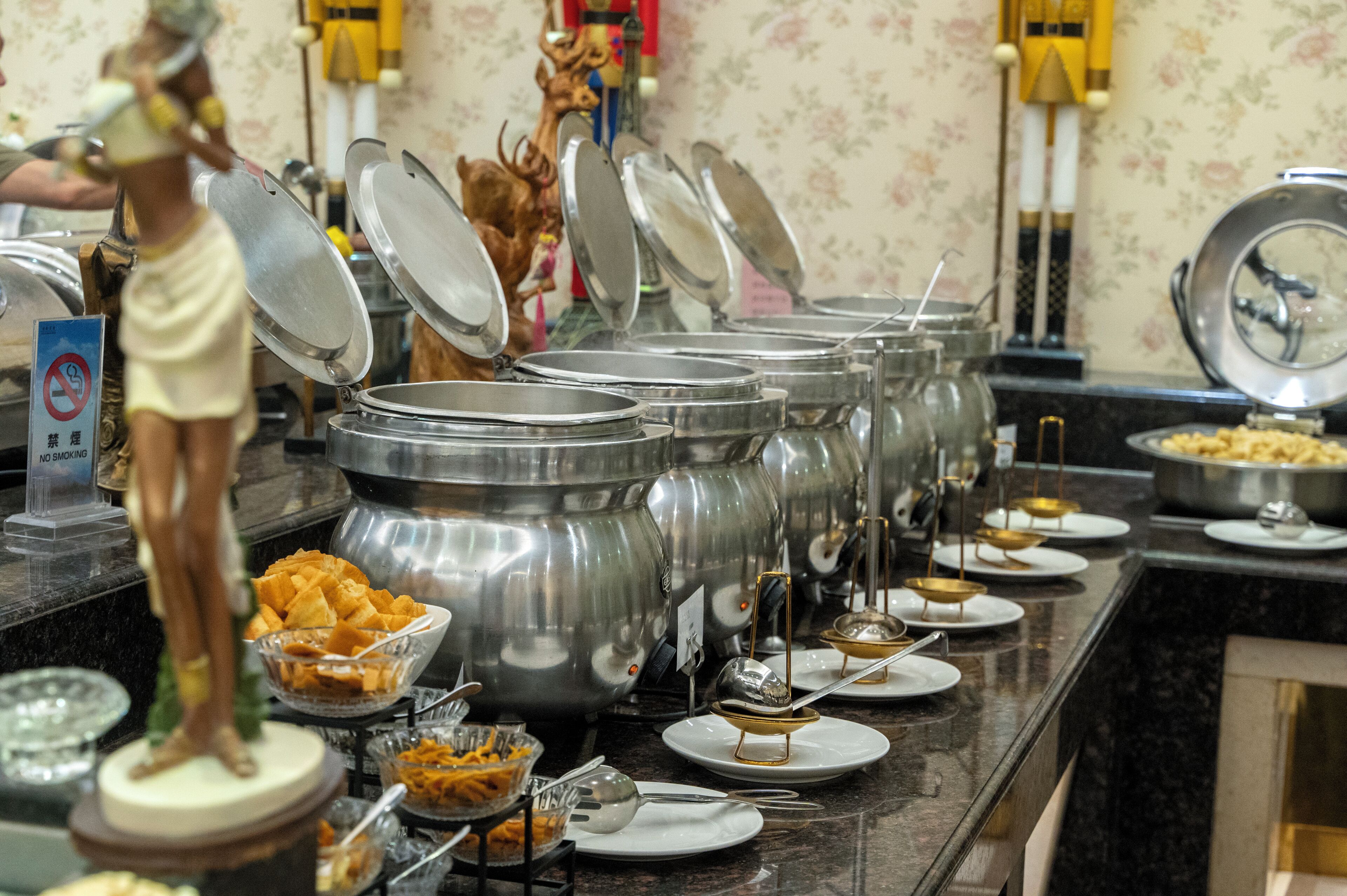 A buffet setup with multiple food containers and serving utensils.