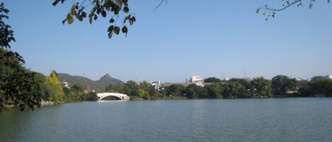 A calm lake with a white bridge and surrounding greenery.