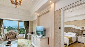 Ett hotellrum med en stor säng, en TV, ett skrivbord och utsikt över staden.