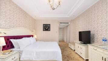 Un dormitorio ordenado con cama, mesitas de noche, televisor y armario.