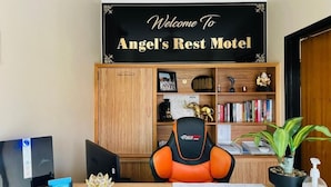A desk with a chair, a computer, and a sign that reads "Welcome to Angel's Rest Motel." - Angel's Rest Motel (Moree)