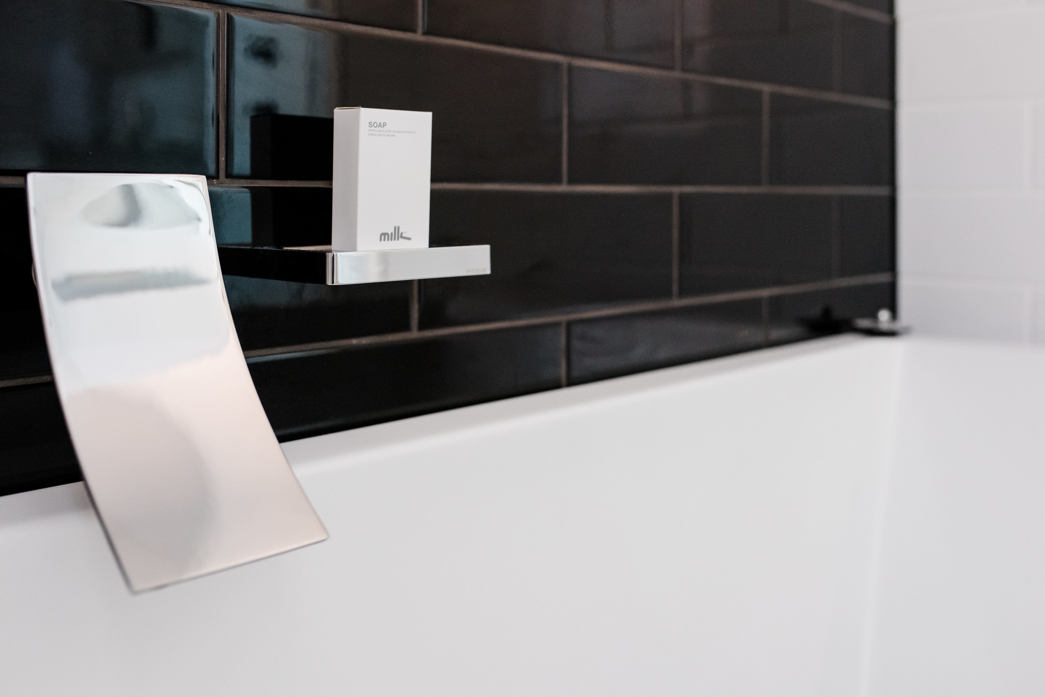 A modern bathroom with a white sink, a soap dispenser, and a mirror.