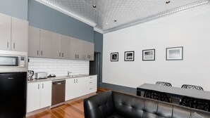 Una cocina moderna con armarios blancos, un refrigerador negro y un comedor con sofá de cuero negro y una mesa.