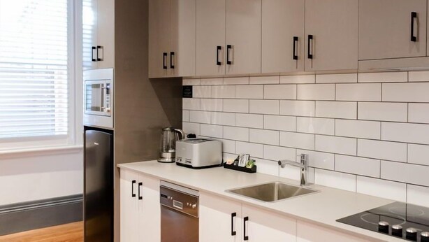 Una cocina moderna con armarios blancos, un fregadero de acero inoxidable y lavavajillas integrado.