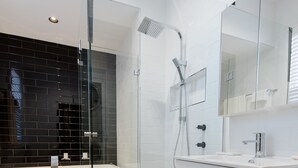 Un baño moderno con ducha envuelta en vidrio, una bañera blanca y un tocador con espejo.