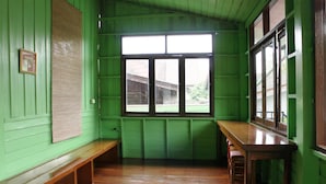 A room with a wooden bench, a window with a view, and a green wall. - Baan Bua Homestay - Hostel (Chiang Rai)