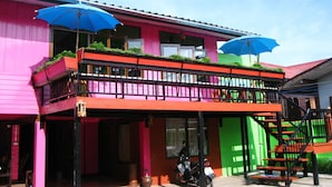 A brightly colored building with a balcony and two blue umbrellas. - Baan Bua Homestay - Hostel (Chiang Rai)