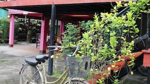 A bicycle parked in front of a building with a balcony and potted plants. - Baan Bua Homestay - Hostel (Chiang Rai)