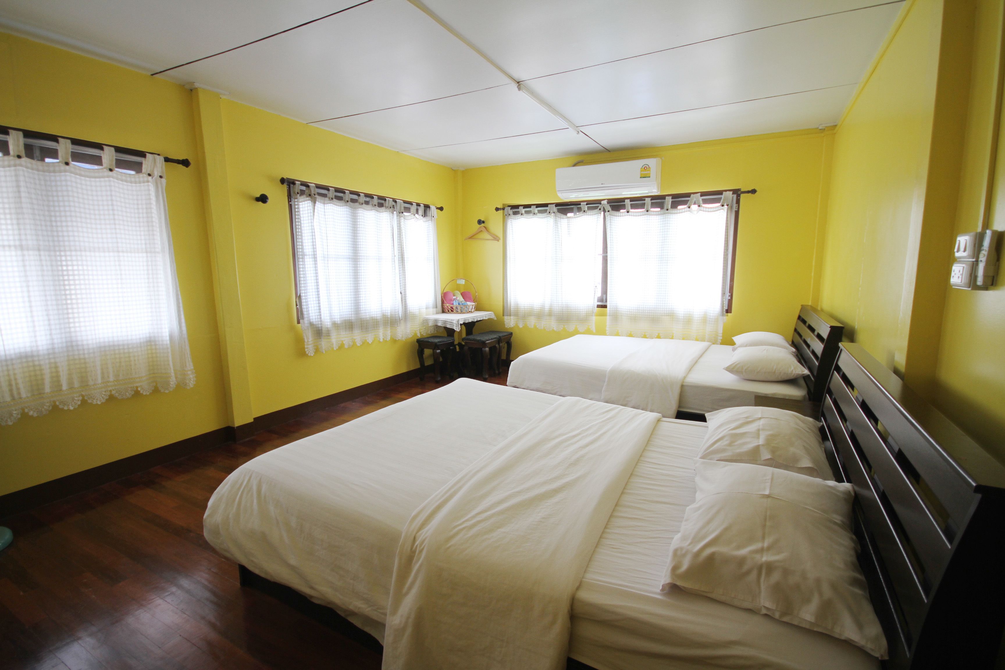 Una habitación con dos camas, paredes amarillas y piso de madera.