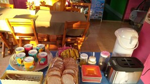 A table set with various food items, including sliced bread, bananas, and a tray of utensils. - Baan Bua Homestay - Hostel (Chiang Rai)