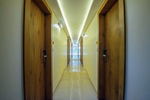 A long, narrow hallway with wooden doors on both sides and a tiled floor.