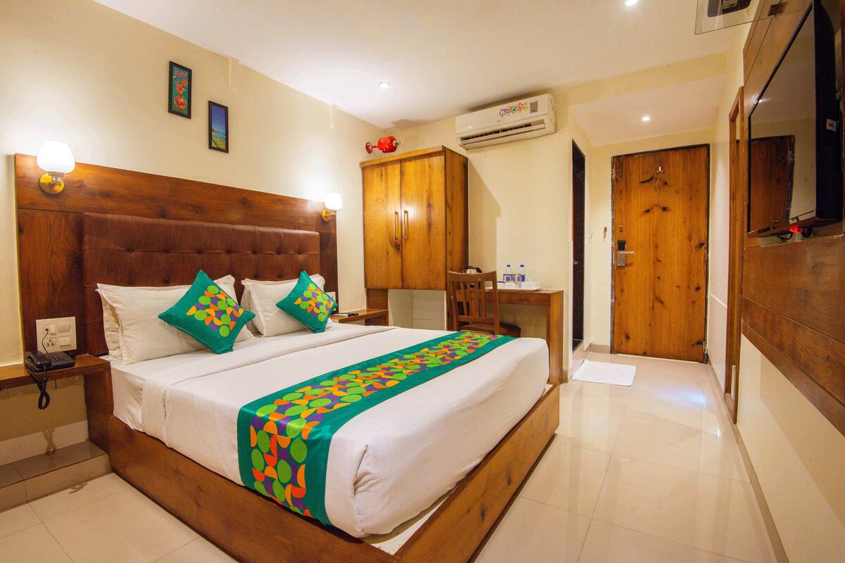 A hotel room with a wooden bed, a desk, an air conditioner, and a wardrobe.