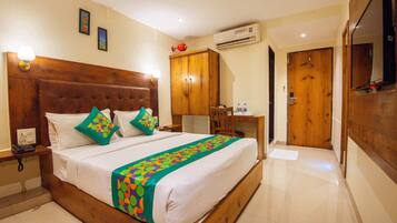 A hotel room with a wooden bed, a desk, an air conditioner, and a wardrobe.