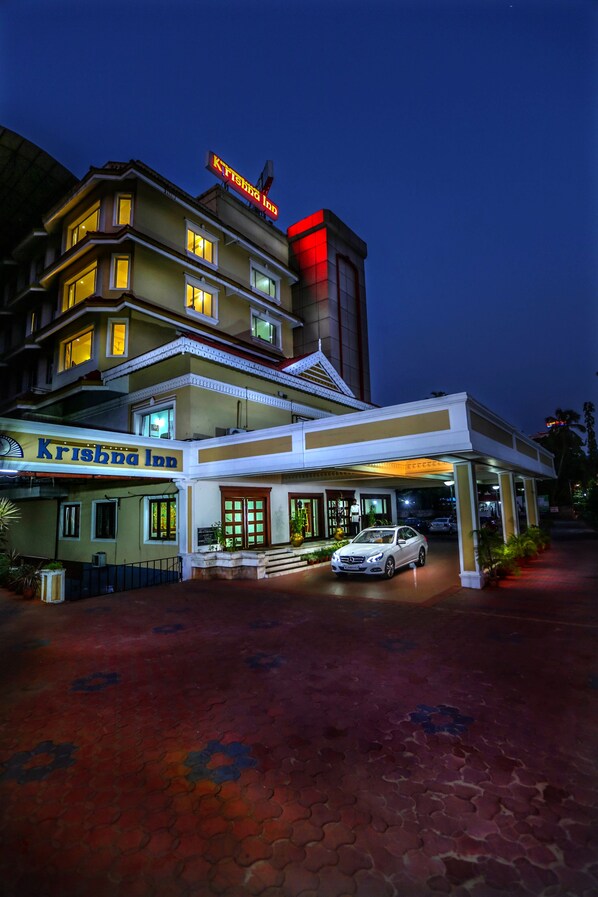 A hotel with a prominent sign reading "Krishna Inn" and a car parked in front.
