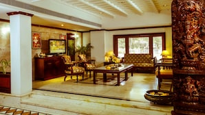 A spacious living room with a high ceiling, wooden furniture, and a large decorative column. - Krishna Inn (Chavakkad)