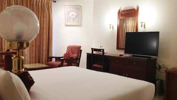 A hotel room with a large bed, a television, a desk, and a chair.