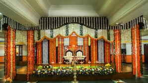 A decorated stage with floral arrangements and a central table, surrounded by chairs. - Krishna Inn (Chavakkad)