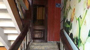 A staircase with stone steps and wooden railings, leading to a room with a floral mural. - Nha Nghi Tham Quyen (Mong Duong)