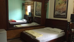 A hotel room with a large bed, a desk, a chair, a television, and a mirror. - Nha Nghi Tham Quyen (Mong Duong)