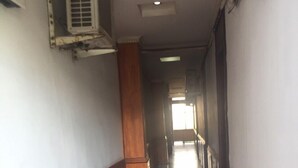 A long, narrow hallway with a wooden floor and walls, leading to a bright area at the end. - Nha Nghi Tham Quyen (Mong Duong)