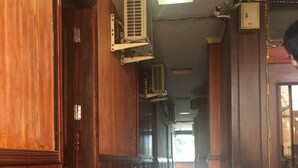 A long hallway with wooden paneling and tiled flooring. There are air conditioning units mounted on the walls. - Nha Nghi Tham Quyen (Mong Duong)