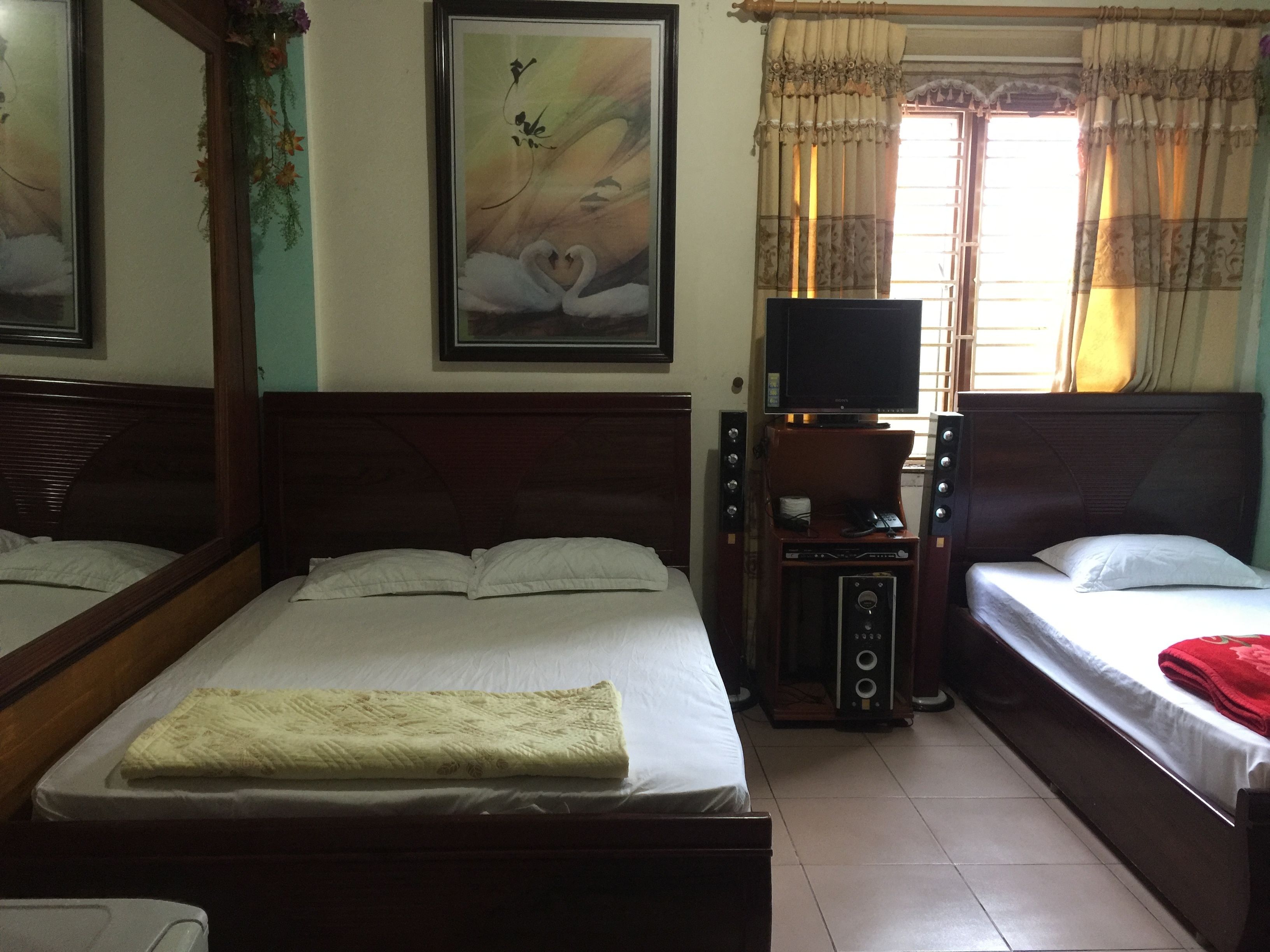 A hotel room with two beds, a television, and a painting on the wall.