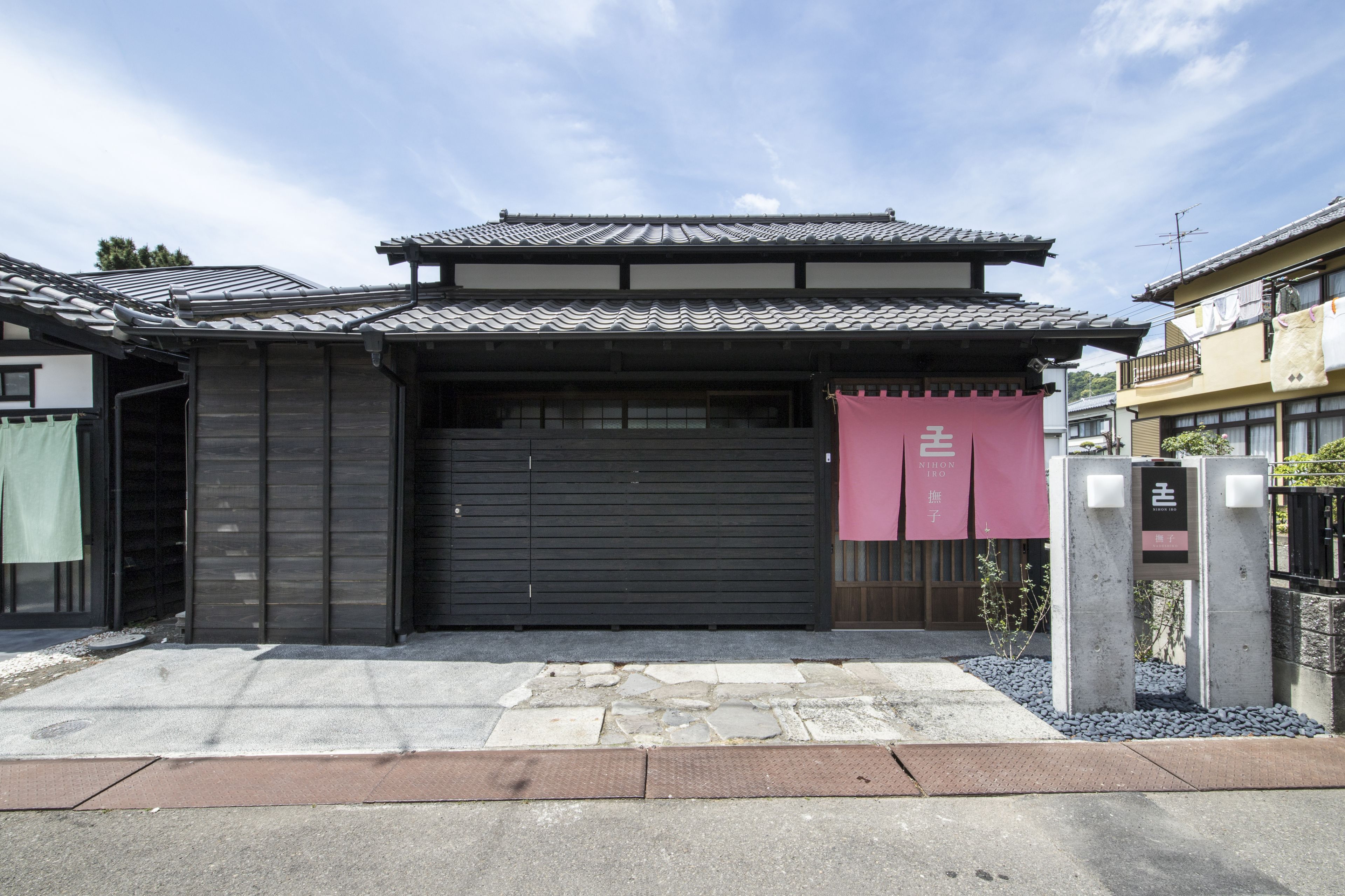 Una casa tradicional japonesa con fachada de madera oscura, tejado de tejas y puerta de garaje cerrada.