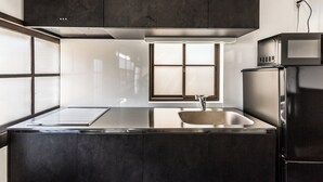 A modern kitchen with dark cabinetry, a stainless steel sink, and a microwave. - Nihon Iro (Shizuoka)