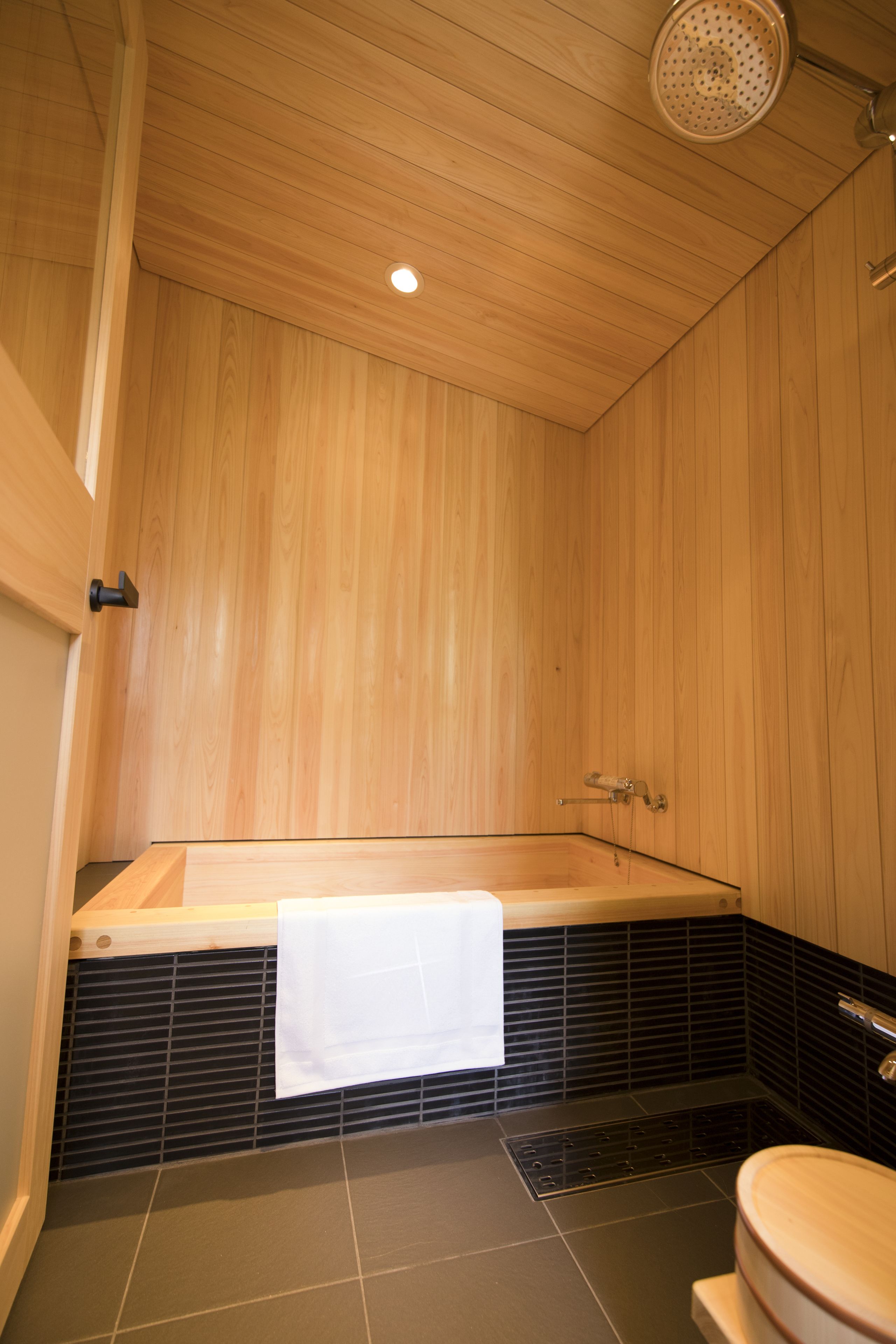 Un baño con paneles de madera, una bañera, un inodoro y una ducha.