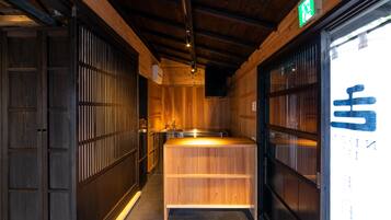 A narrow hallway with wooden walls and a central wooden counter. There is a green exit sign above the counter.