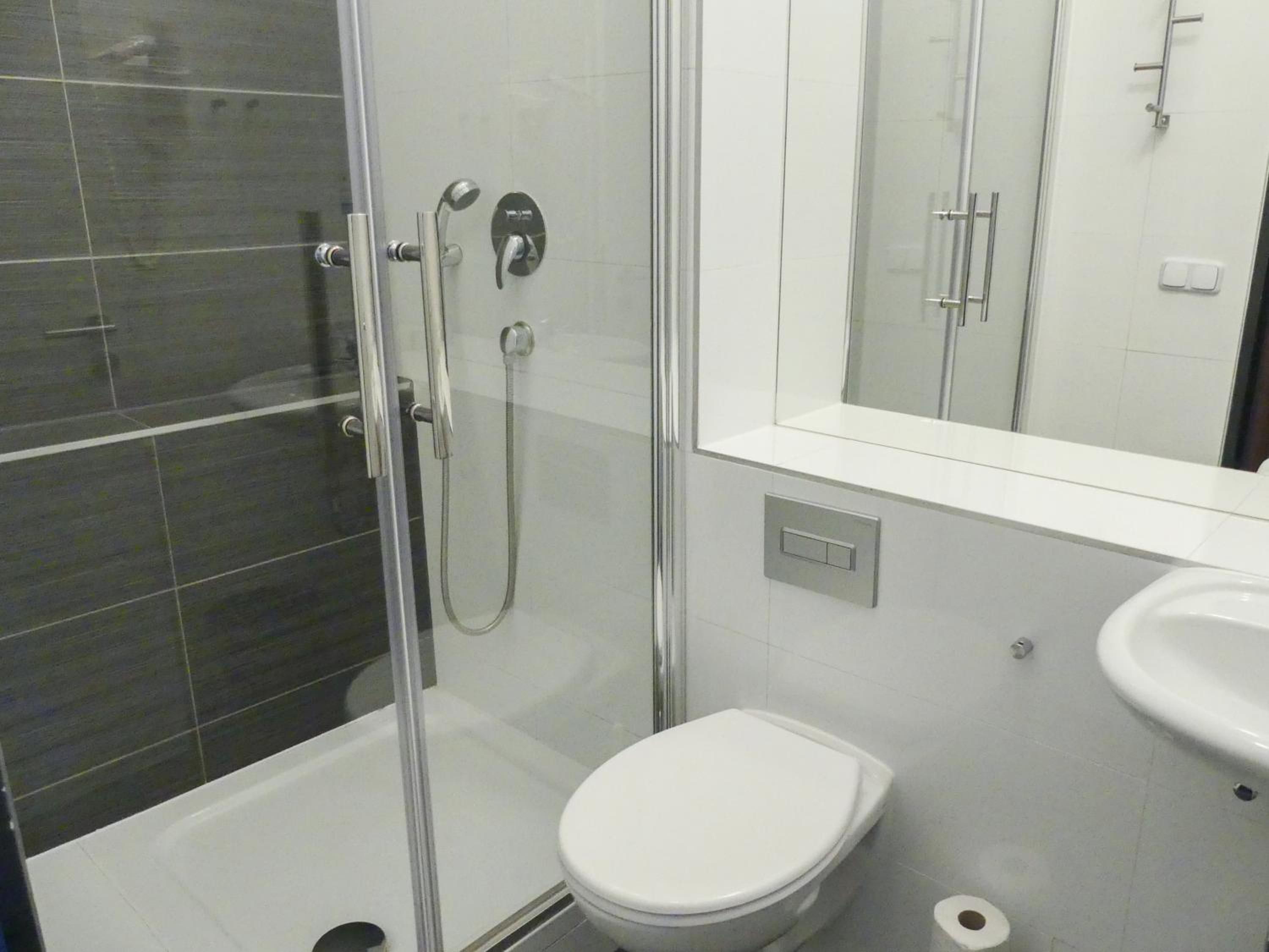Moderni kylpyhuone, jossa on lasiseinällä varustettu suihku, wc ja pesuallas.