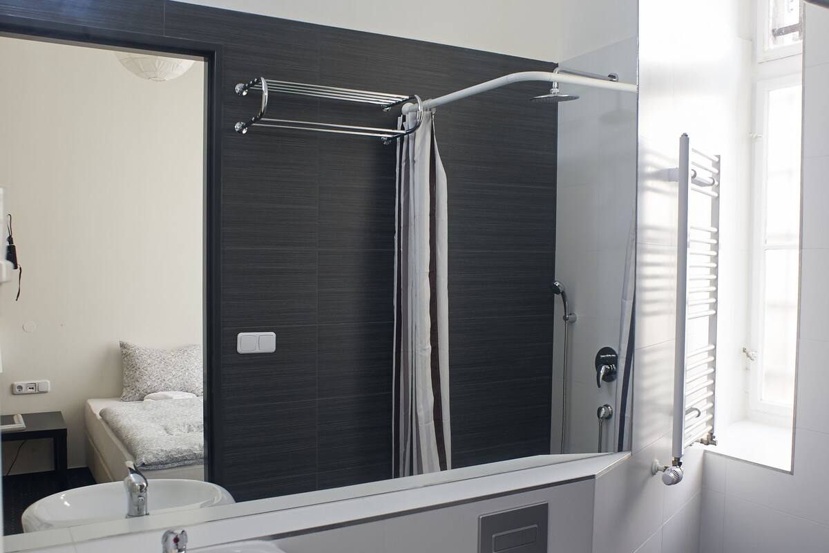 A modern bathroom with a white sink, a toilet, a large mirror, and a shower area.