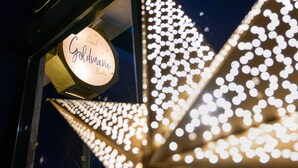 Et hotelskilt med navnet 'Hotel Goldmarie Berlin' og dekorativ belysning.