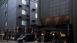 Un bâtiment moderne à la façade sombre, doté de grandes fenêtres et d’un élément de design vertical distinctif.