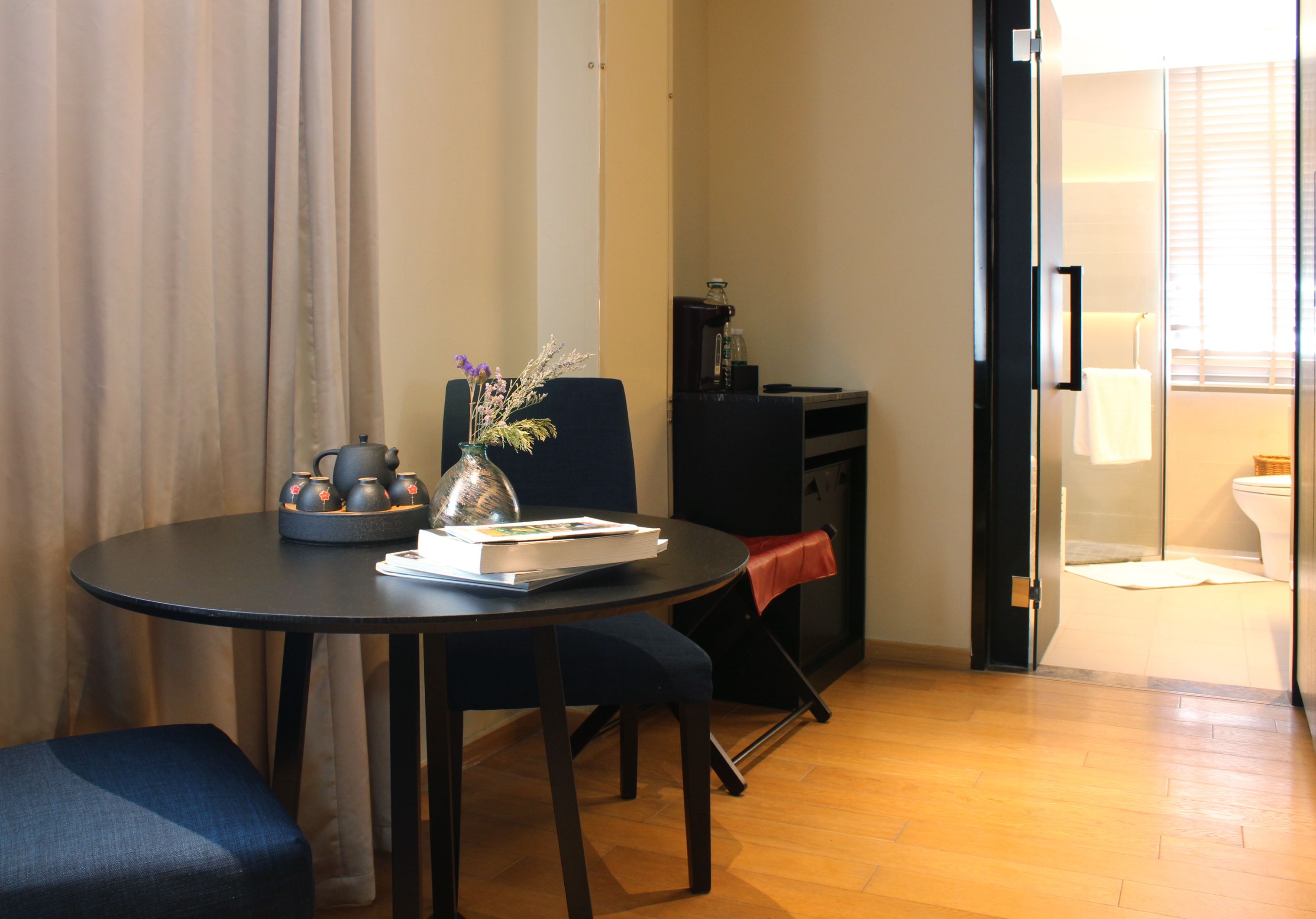 A compact living space with a dining table, a sofa, a small kitchen area, and a bathroom visible through an open door.