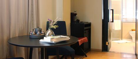 A compact living space with a dining table, a sofa, a small kitchen area, and a bathroom visible through an open door.