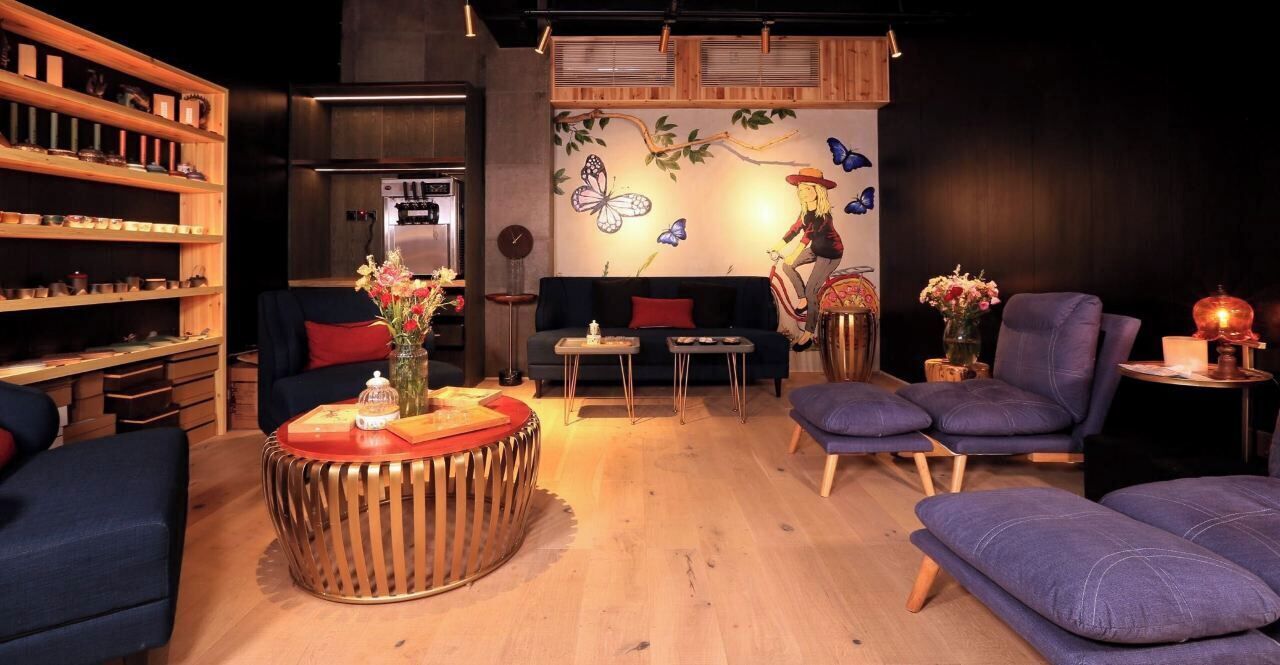Una sala de estar acogedora con una estantería de madera, una mesa de centro redonda y un mural con mariposas.