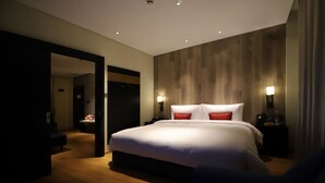 Une chambre d’hôtel moderne avec un grand lit, un mur recouvert de panneaux en bois et deux lampes de chevet.