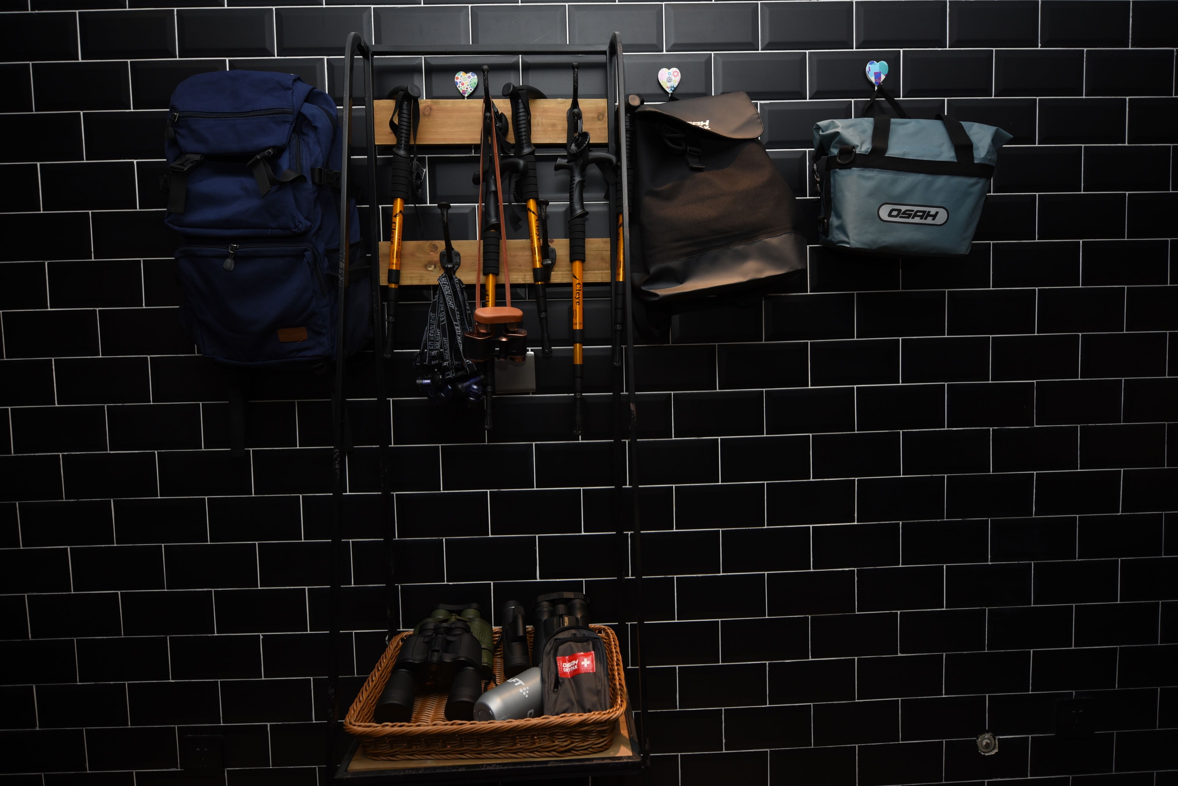 A wall-mounted rack with various bags and gear, a blue backpack, and a basket with items.