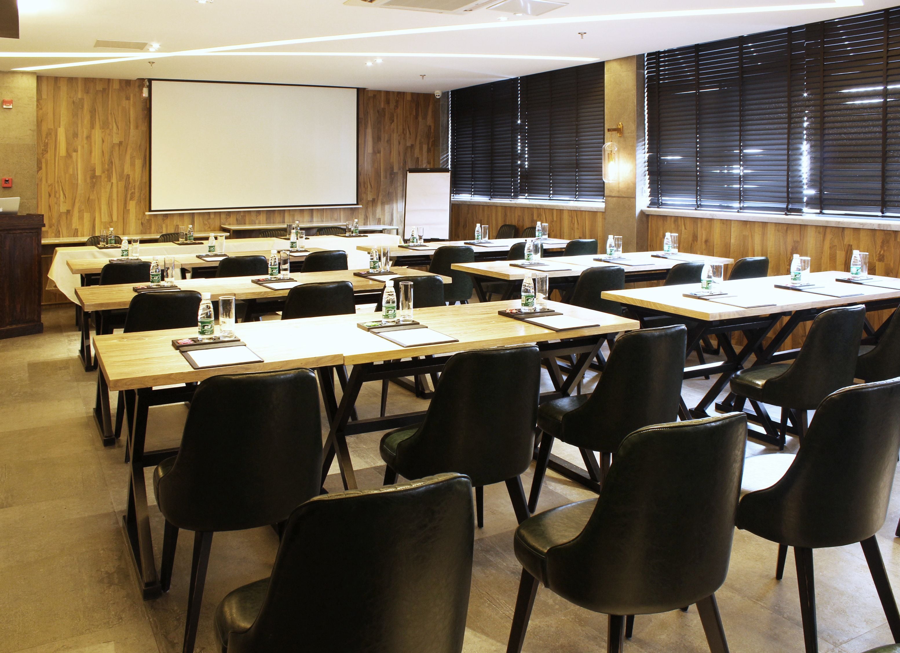 Une salle de conférence dotée de plusieurs tables et de chaises, ainsi que de bouteilles d’eau et de blocs-notes.