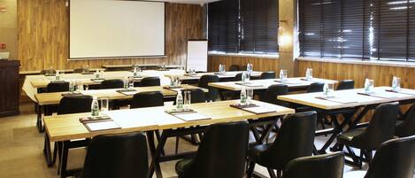 A conference room with multiple tables and chairs, equipped with water bottles and notepads.