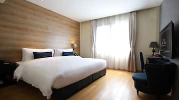 A modern hotel room with a large bed, a desk, and a television.
