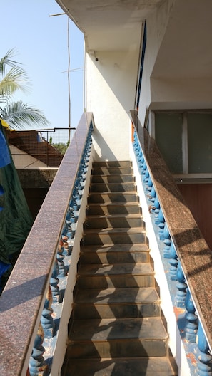 Un escalier avec des balustrades bleues et une main courante, menant à l’entrée d’un bâtiment.