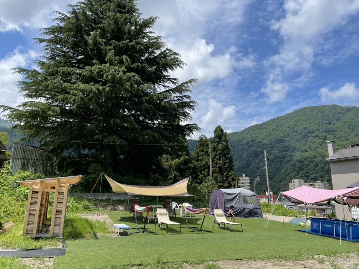 Un camping con tiendas de campaña, una estructura de madera y un árbol grande.