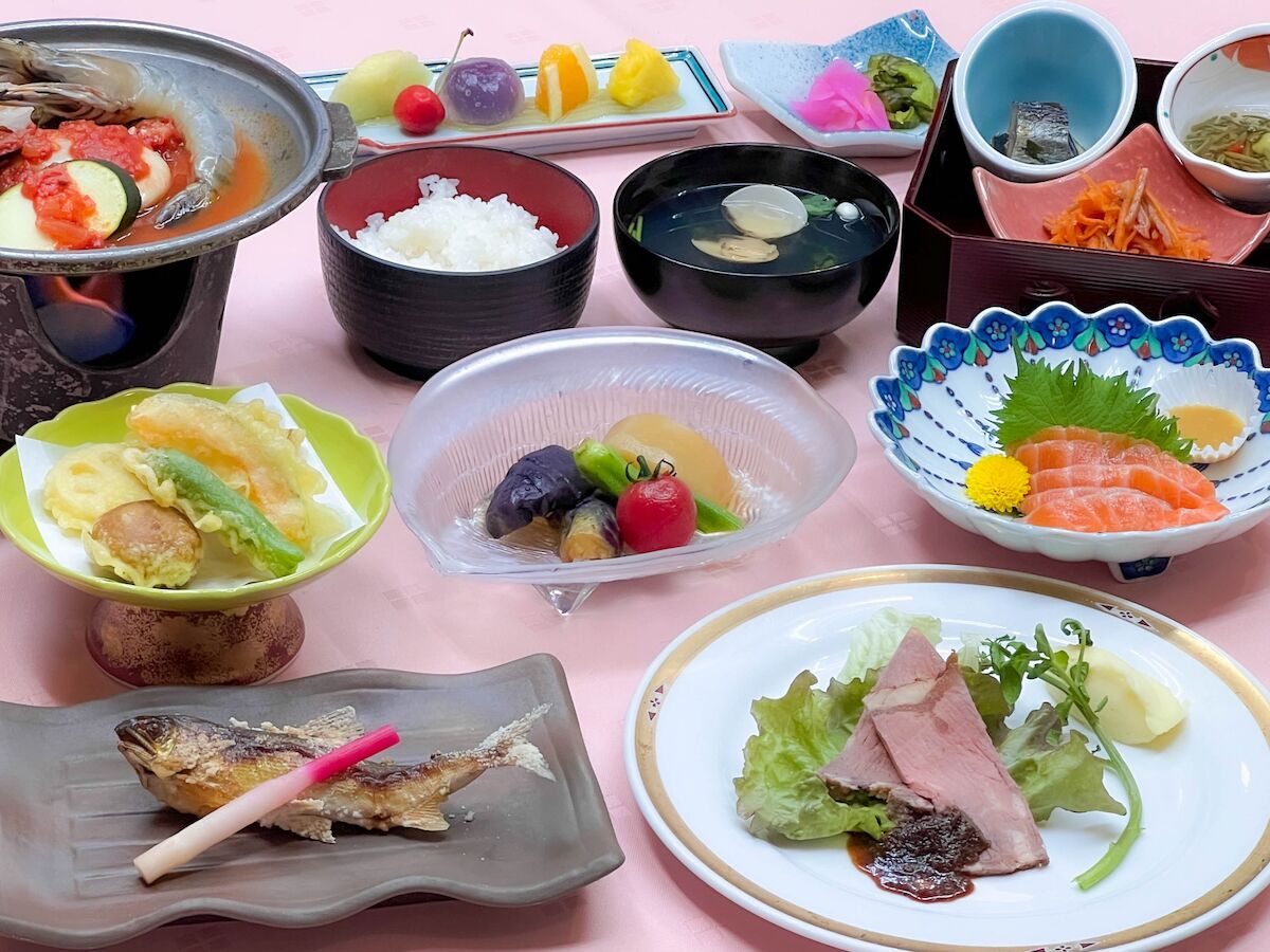 A variety of dishes including fish, rice, and vegetables on a pink table.