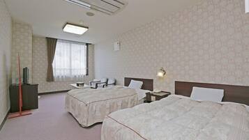 Een hotelkamer met twee bedden, een bureau, een stoel, een televisie en een raam met gordijnen.